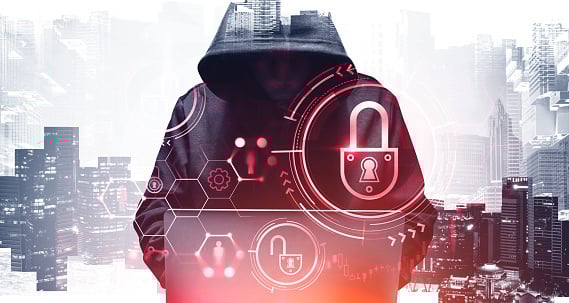 Unrecognizable young hacker in hoodie using laptop in blurry city. Concept of cybersecurity. Toned image. Double exposure of security interface