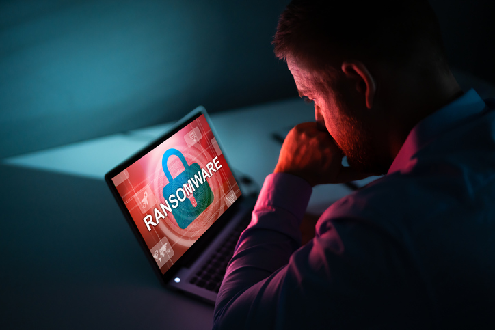 Worried Businessman Looking At Laptop With Ransomware Word On The Screen At The Workplace